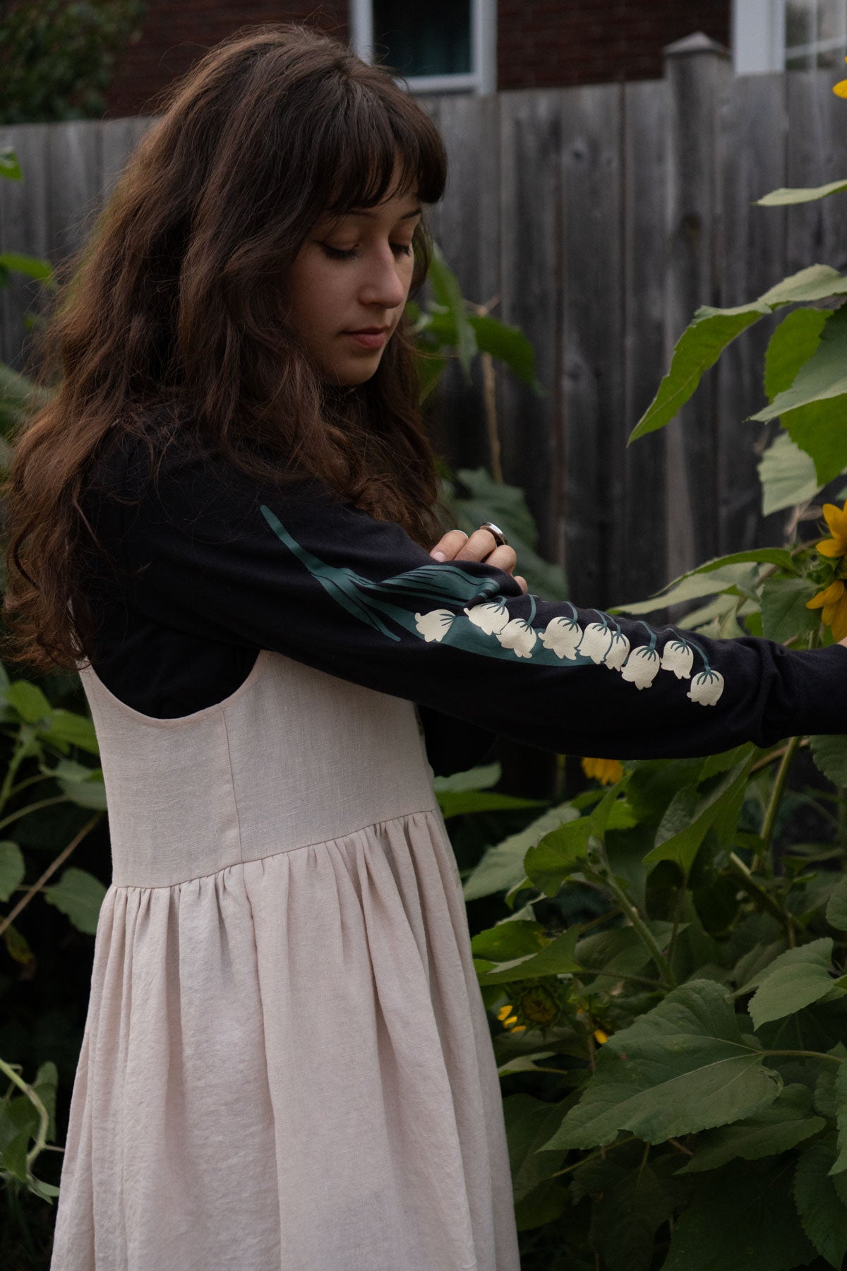 Woman wearing a black long-sleeved tee with white floral patterns in a garden setting
