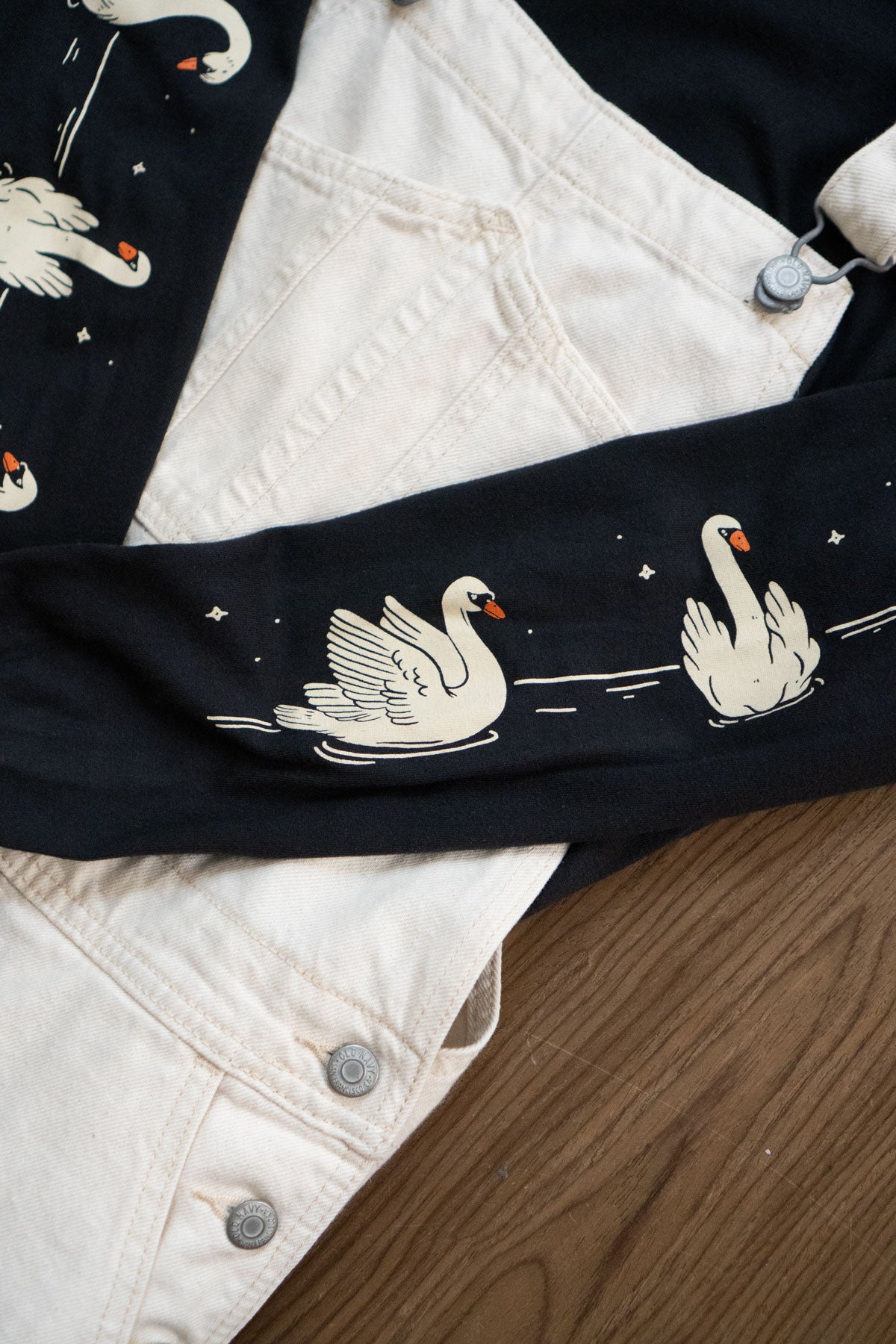 Close-up of a black long-sleeved tee with white swan designs 