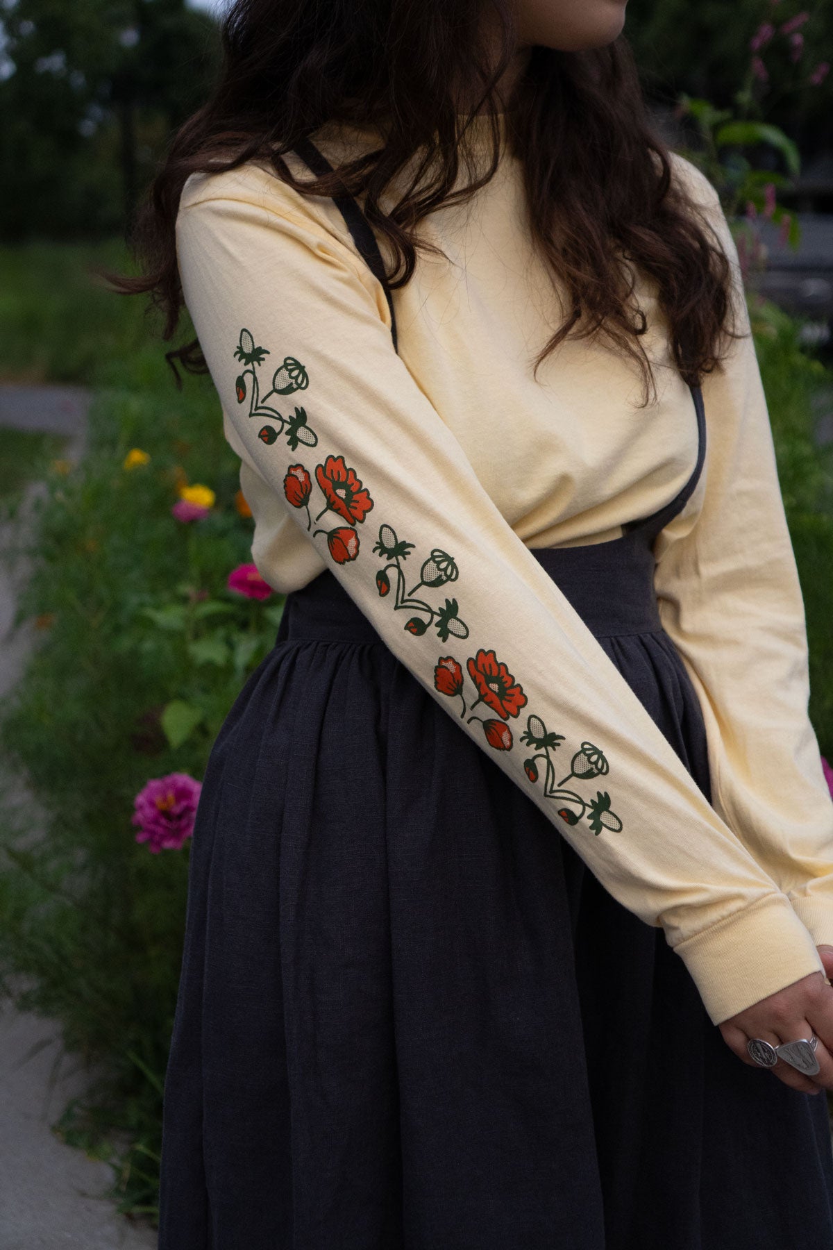Person wearing a butter yellow long-sleeve shirt with floral sleeve prints, standing outdoors.