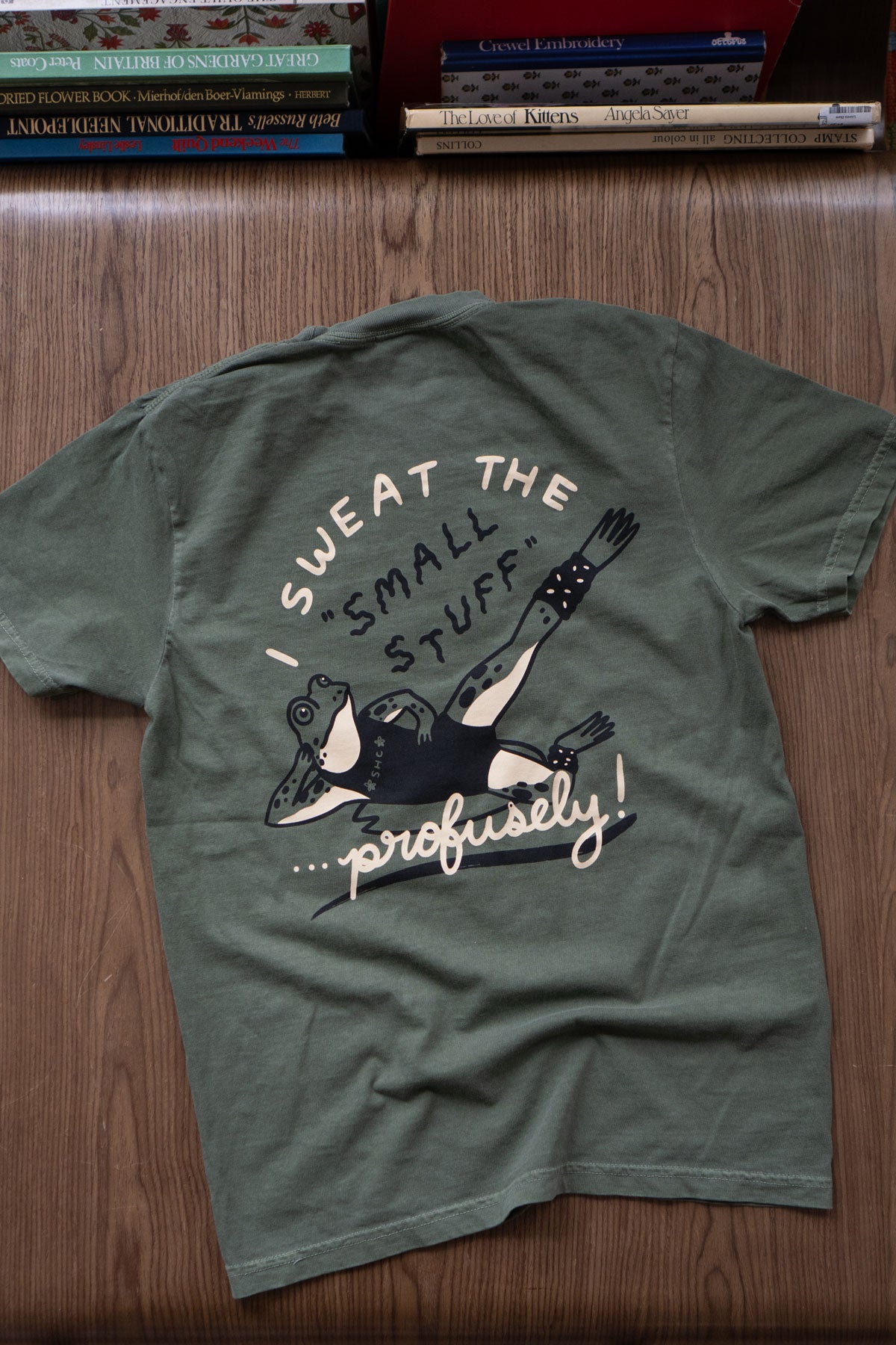 Deep green t-shirt featuring an anxious frog print, seen from the back