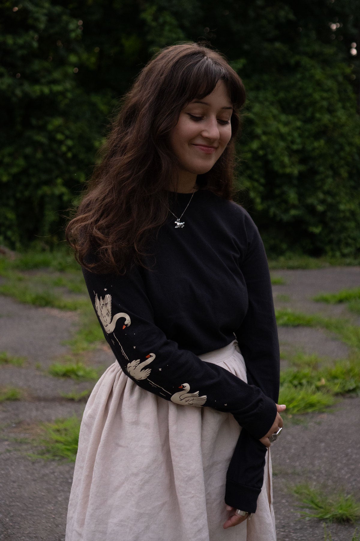 Woman wearing a black long-sleeved t-shirt with swans printed down the sleeves