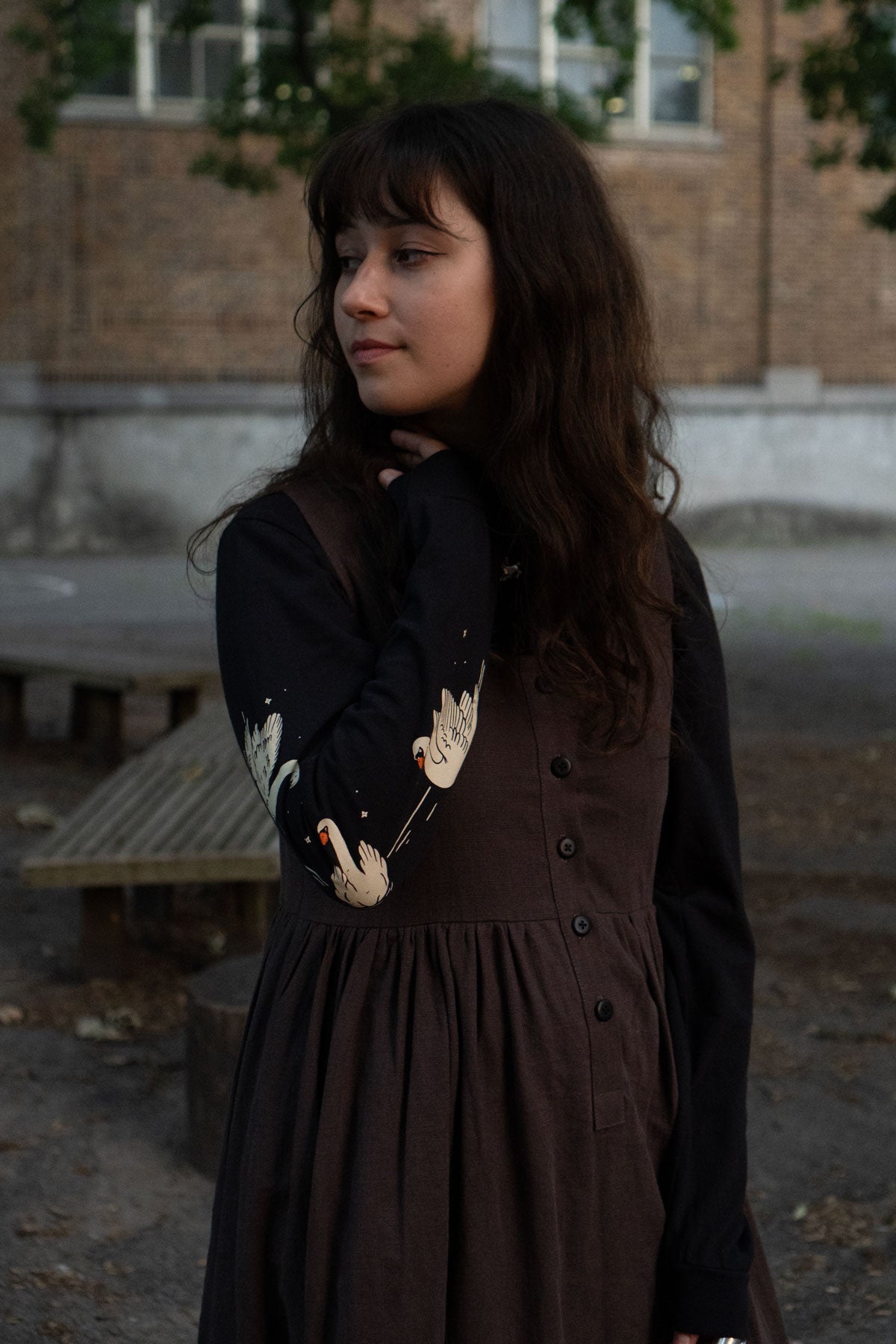 Woman wearing a dark dress with a patterned long-sleeve tee in an outdoor setting