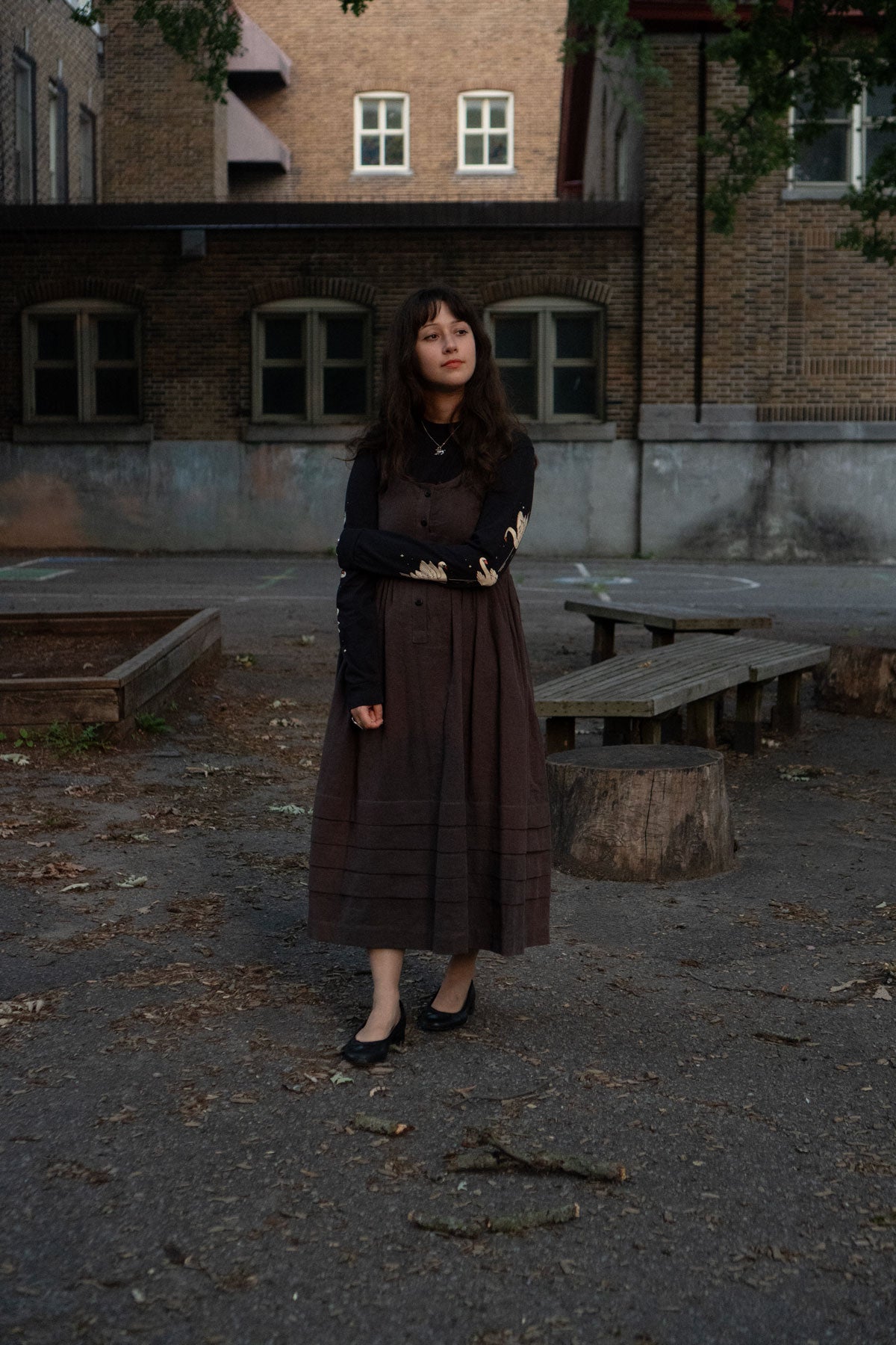 Woman standing in an urban setting with a brick building in the background